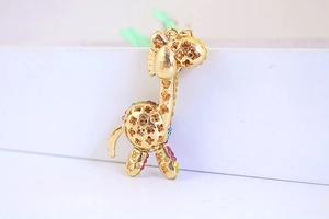 Dettaglio di un ciondolo a giraffa dorata con strass colorati e texture a quadrifoglio