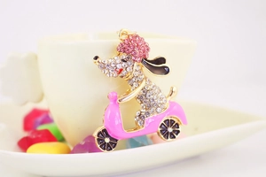 Detalle de caniche con diamantes de imitación en scooter rosa para llavero de metal
