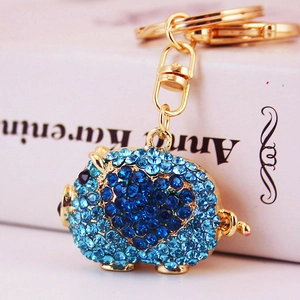 Sparkling blue rhinestone pig keychain with golden metal ring near Anna Karenina book