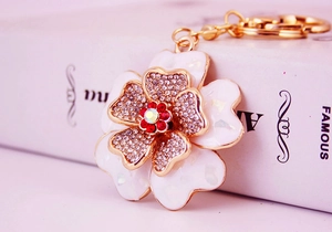 Close-up of floral keychain with white enamel petals and sparkling rhinestones
