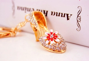 Macro detail of high heel keychain featuring gold plating, rhinestones and enamel daisy flower