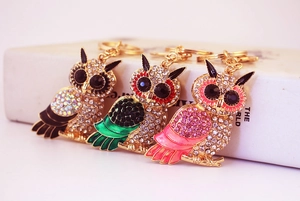 Detailed macro view of colorful owl keychains with inlaid rhinestones and enamel wings