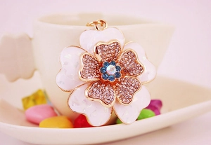Detailed shot of enamel flower charm with pink rhinestones and a blue gemstone core