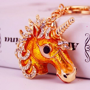 Sparkling crystal unicorn keychain with orange enamel detail on a gold metal base