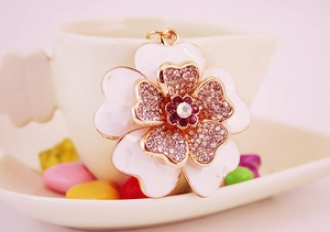 Macro shot of shell peony keychain with white enamel petals and purple crystals