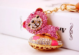 Close-up of pink crystal bear keychain with golden heart and enamel flower detail
