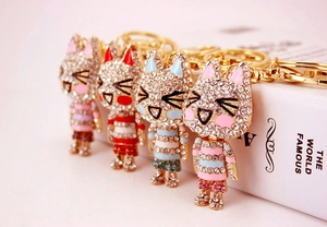 Detail view of four crystal-studded cat keychains in various colors on a white book