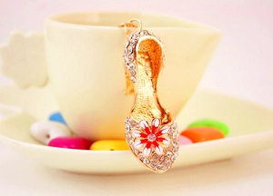 Detail of crystal high heel shoe keychain with enamel daisy flower on a coffee cup