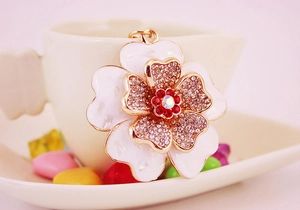 Macro detail of alloy shell peony keychain with white enamel petals and red rhinestones