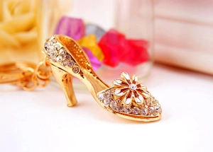 Macro detail of golden high-heeled shoe keychain with crystal rhinestones and daisy flower
