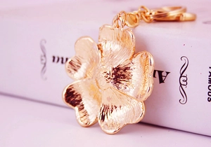 Close-up of golden flower keychain with brushed metal texture and shell petal details