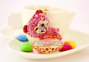 Detail of crystal sleeping bear keychain with pink rhinestones on golden hollow base