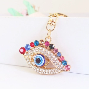 Porte-clés œil protecteur en métal doré serti de strass brillants et cristaux colorés