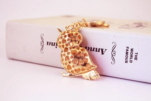 Detailed close-up of golden owl keychain featuring heart-shaped hollow-out patterns