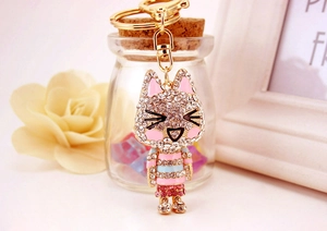Detail of cute rhinestone cat keychain with pink enamel ears and striped outfit