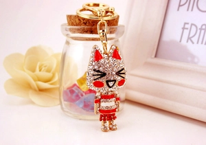 Close-up of golden kitten keychain with sparkling rhinestones and red enamel details