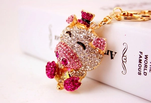 Close-up of cute cartoon pig keychain with pink rhinestones on a gold alloy base