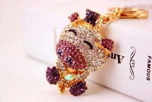 Side view of crystal pig keychain with purple rhinestones on golden alloy base