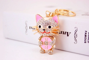 Macro detail of golden crystal cat keychain with white rhinestones and pink charm