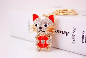 Close-up of golden Maneki Neko keychain with sparkling crystals and red enamel accents