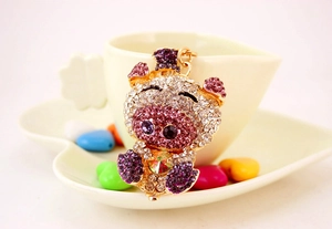 Close-up of cute crystal pig keychain with pink rhinestones on a heart-shaped cup