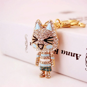 Creative cat keychain with blue rhinestones and gold plating on a white book