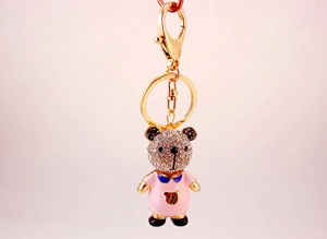 Détail macro d'un porte-clés ours en cristal avec émail rose et finition dorée élégante