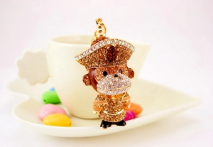 Détail d'un porte-clés singe en strass posé sur une tasse à café avec des bonbons cœurs
