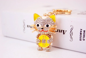 Macro view of gold lucky cat keychain with white crystals and lucky coin detail