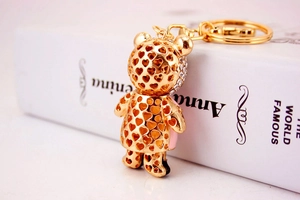 Détail d'un porte-clés ours doré avec motifs de cœurs évidés et strass brillants de luxe