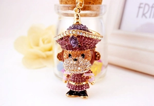 Détail d'un porte-clés singe orné de strass violets et roses sur une base en alliage doré
