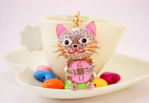 Close-up of golden Maneki Neko keychain with sparkling rhinestones and lucky charm coin