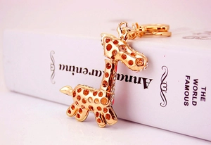 Détail d'un porte-clés girafe doré avec des strass blancs étincelants et des motifs ajourés