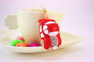 Close-up of red car keychain with rhinestones hanging on a cream ceramic cup