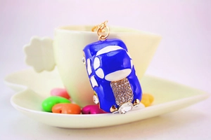 Close-up of blue rhinestone car keychain hanging on a yellow coffee cup with heart candies