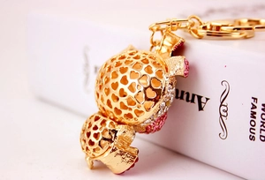 Detailed macro view of golden turtle keychain with pink crystals and heart hollow pattern