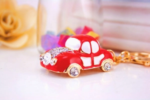 Macro shot of red vintage car keychain with sparkling crystals and golden metal ring