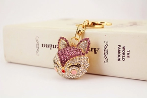 Detailed close-up of a fox-shaped rhinestone keychain with pink crystals on a white book