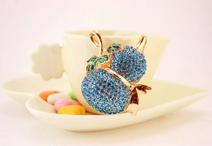 Dettaglio ravvicinato di un ciondolo a zucca con strass blu sul bordo di una tazza bianca
