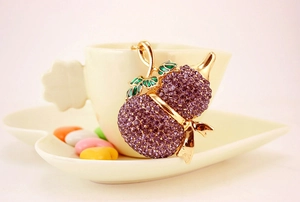 Dettaglio di un portachiavi a forma di zucca dorata con strass viola e foglia in smalto