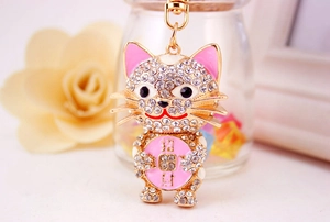 Macro detail of crystal encrusted lucky cat keychain with pink enamel ears and gold finish