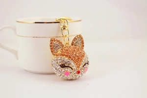Detailed view of fox keychain with champagne rhinestones on a white porcelain cup
