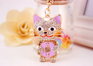 Detailed close-up of sparkling crystal-studded lucky cat keychain with purple accents