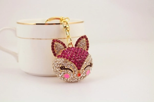 Detailed view of fox keychain with pink rhinestones hanging on a white ceramic cup
