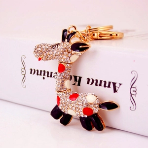 Golden giraffe keychain with sparkling white rhinestones and red enamel spots on a book