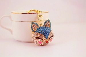 Detailed close-up of a blue crystal fox keychain with gold plating on a coffee cup