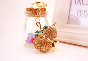 Dettaglio macro di un portachiavi a forma di zucca dorata con strass color champagne lucidi