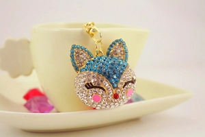 Close-up of cute fox keychain with sparkling blue and white rhinestones on gold alloy base
