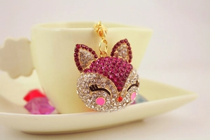 Close-up of cute fox keychain with pink and white rhinestones hanging on a coffee cup