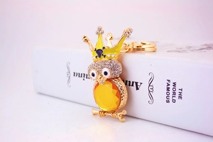 Détail du porte-clés hibou doré avec pierre précieuse jaune et couronne sur livre